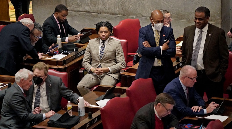 A group of people in suits, some standing and some sitting, in a room.