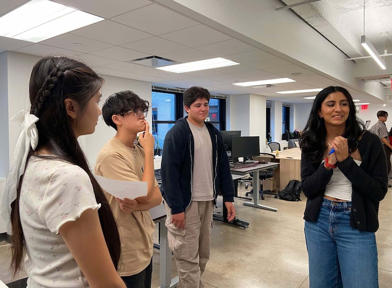 A group of students work in a white classroom